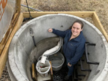 Woman standing inside a tile drainage research monitoring pipe on a farm.