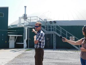 Man in front of building that holds manure digester